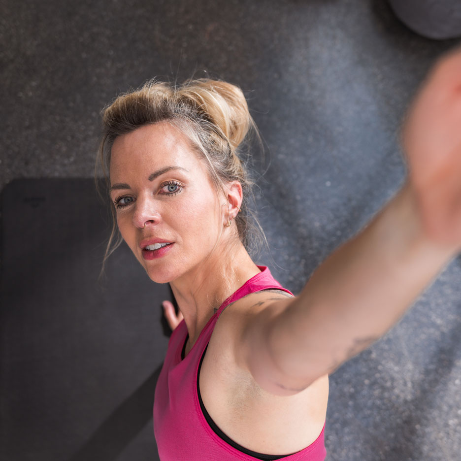 Una donna in top sportivo rosa si scatta un selfie in palestra.