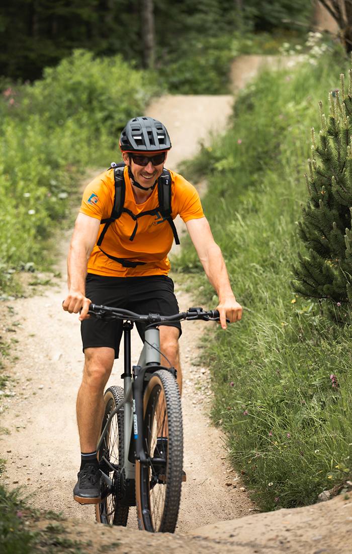 Un uomo sorride mentre va in mountain bike su un sentiero.