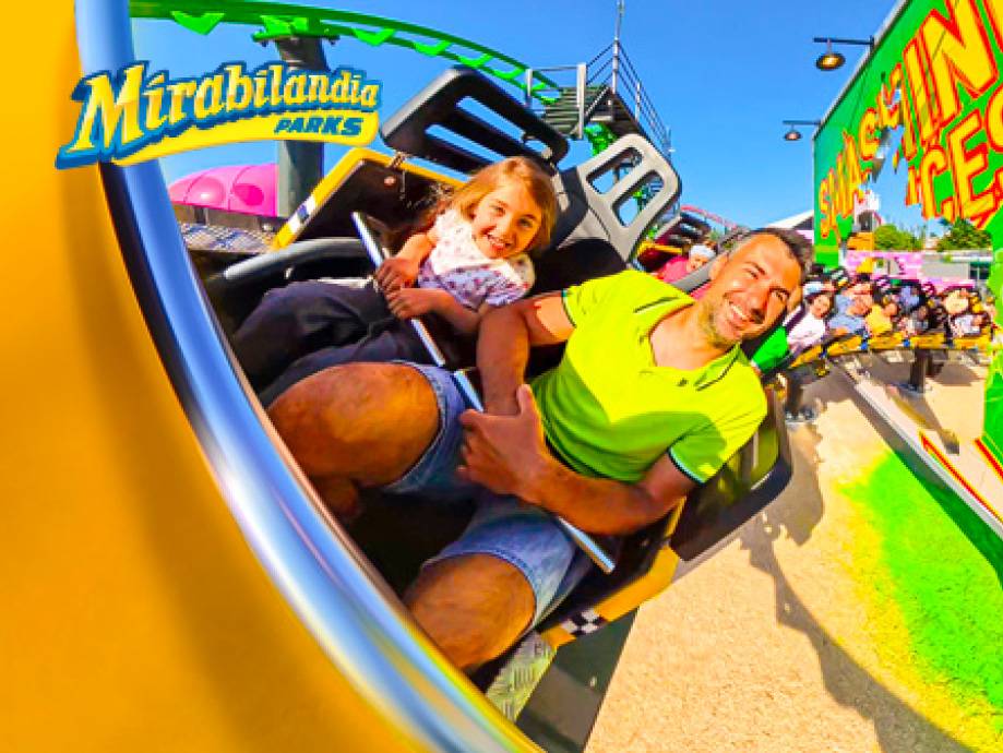 Padre e figlia sorridono su una giostra in un parco divertimenti.