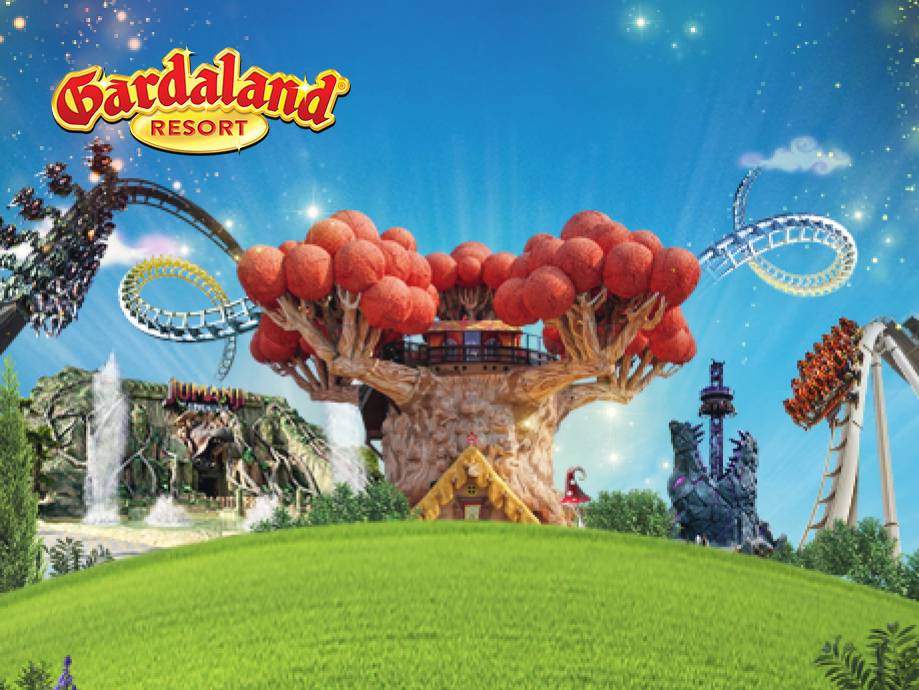 Parco divertimenti con montagne russe, attrazioni e un grande albero rosso, con il logo 'Gardaland Resort'.