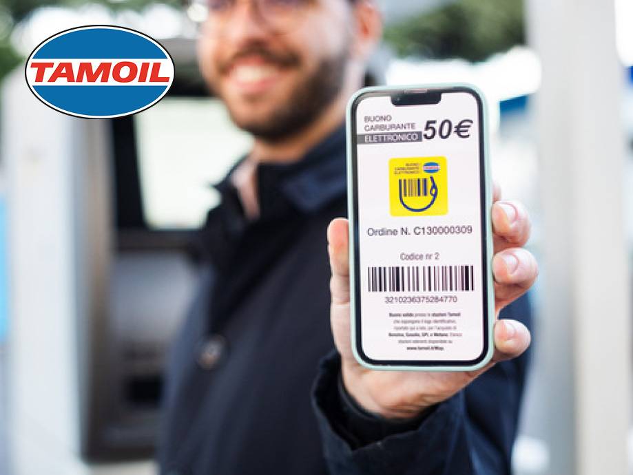 Uomo sorridente mostra un buono carburante elettronico da 50€ sul suo smartphone.