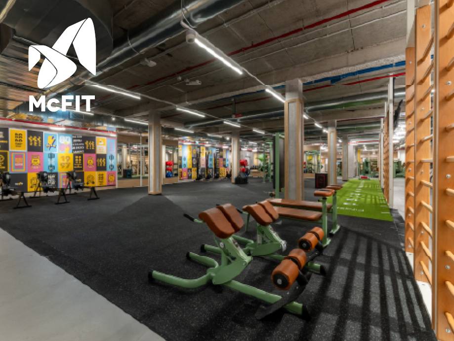 Interno di una palestra moderna con attrezzature per l'allenamento e pareti colorate.
