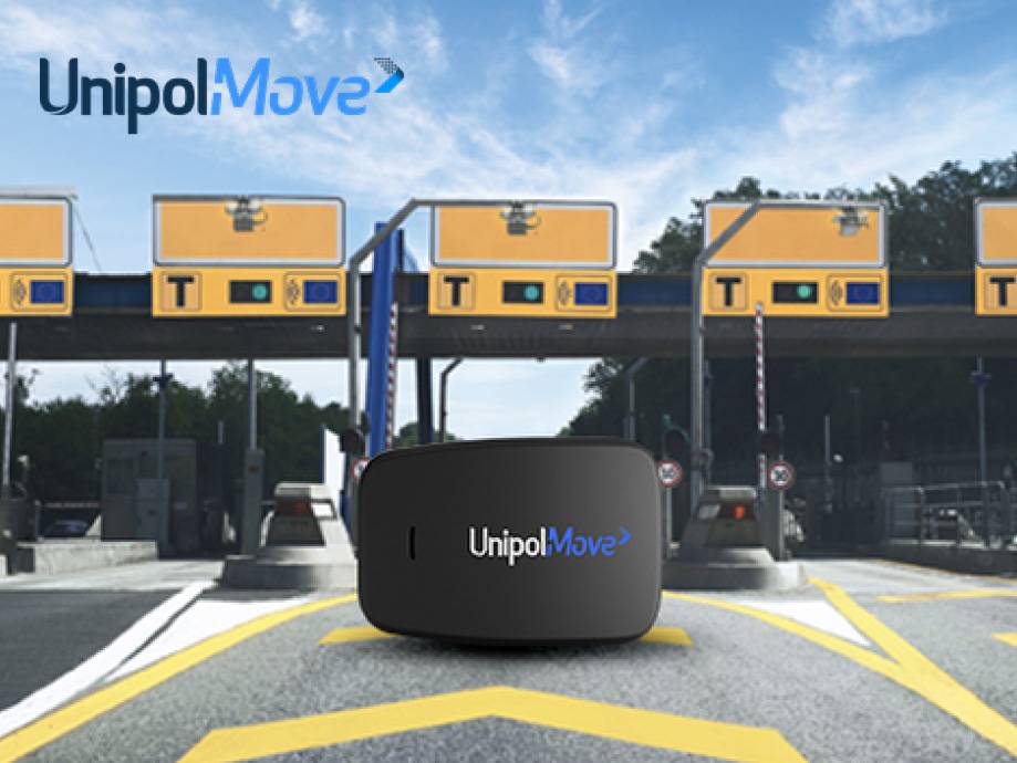 Dispositivo nero per telepedaggio con logo su strada, con caselli autostradali sullo sfondo.