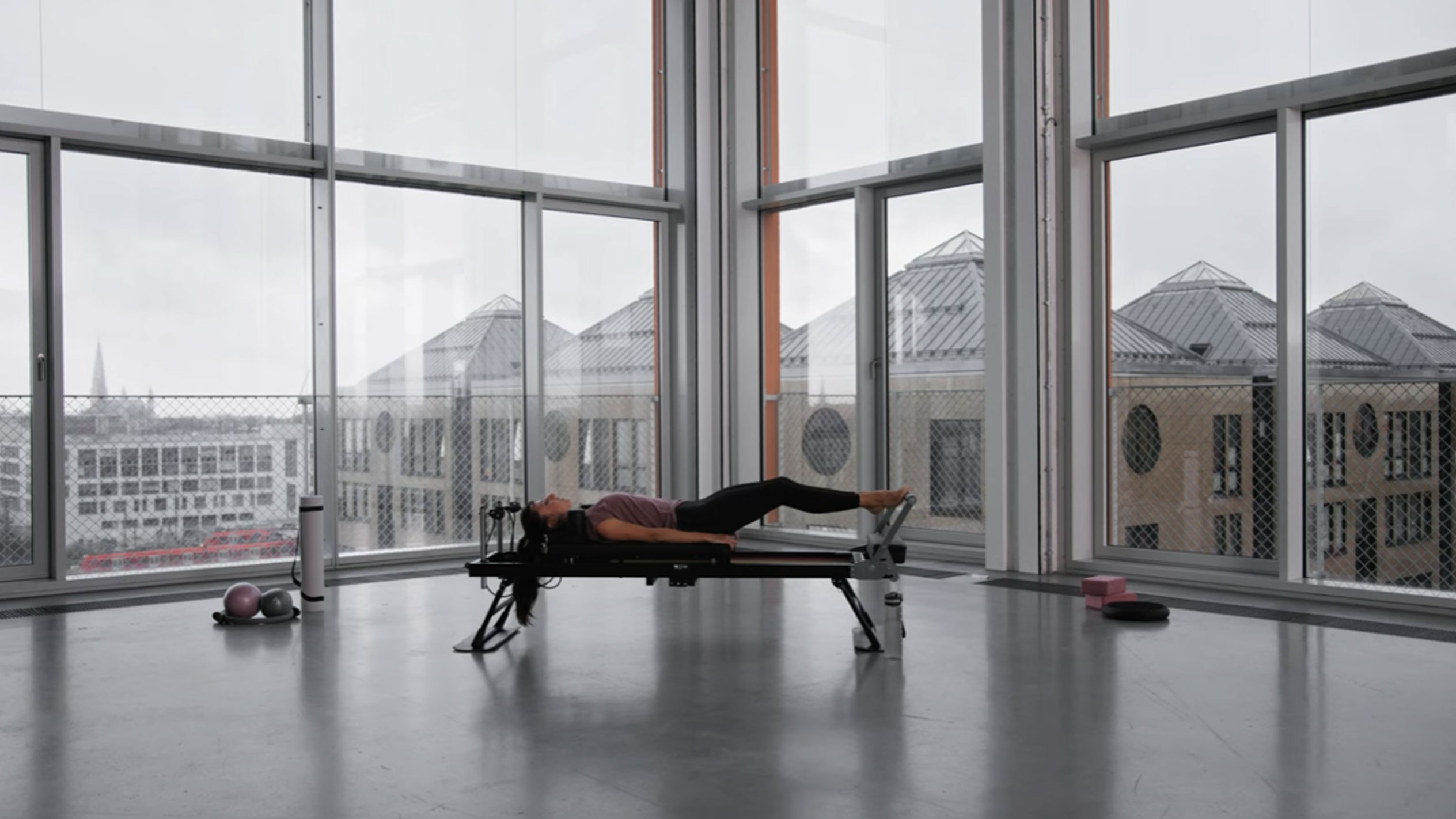 Donna che fa Pilates in uno studio moderno con vista sulla città.