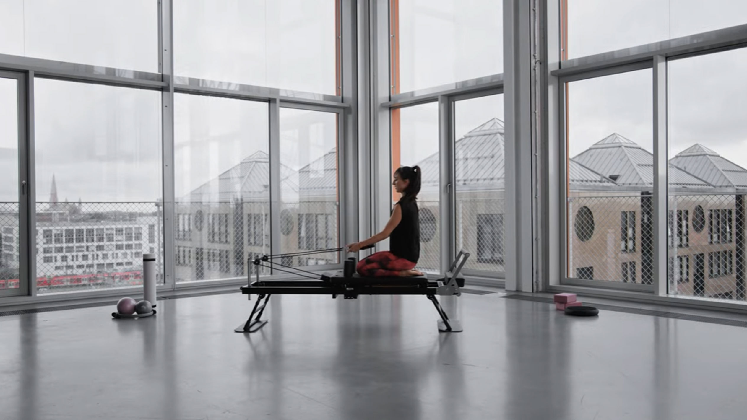 Donna che fa Pilates su un reformer, con vista sulla città.