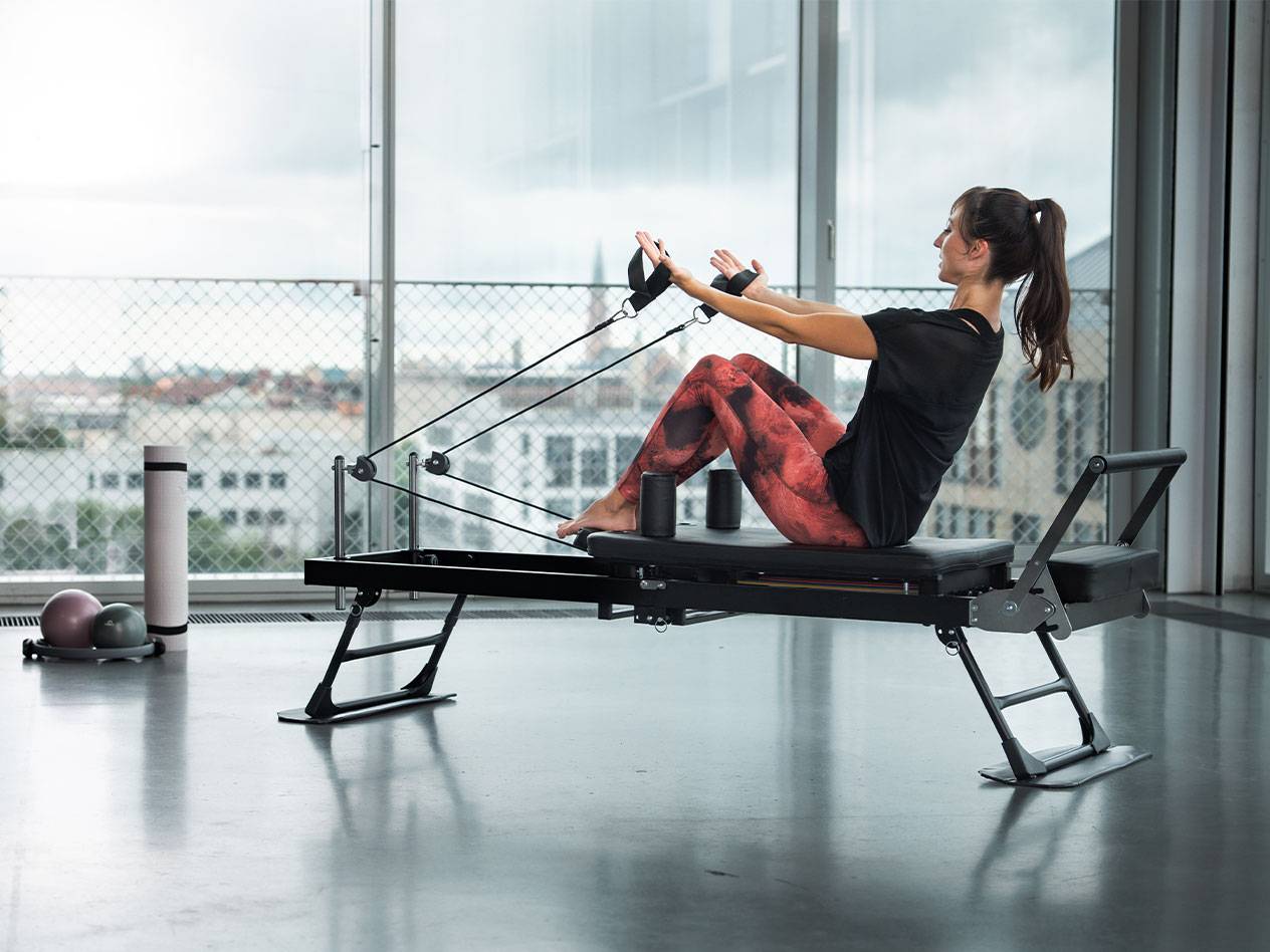 Donna che fa Pilates su un reformer con vista sulla città.