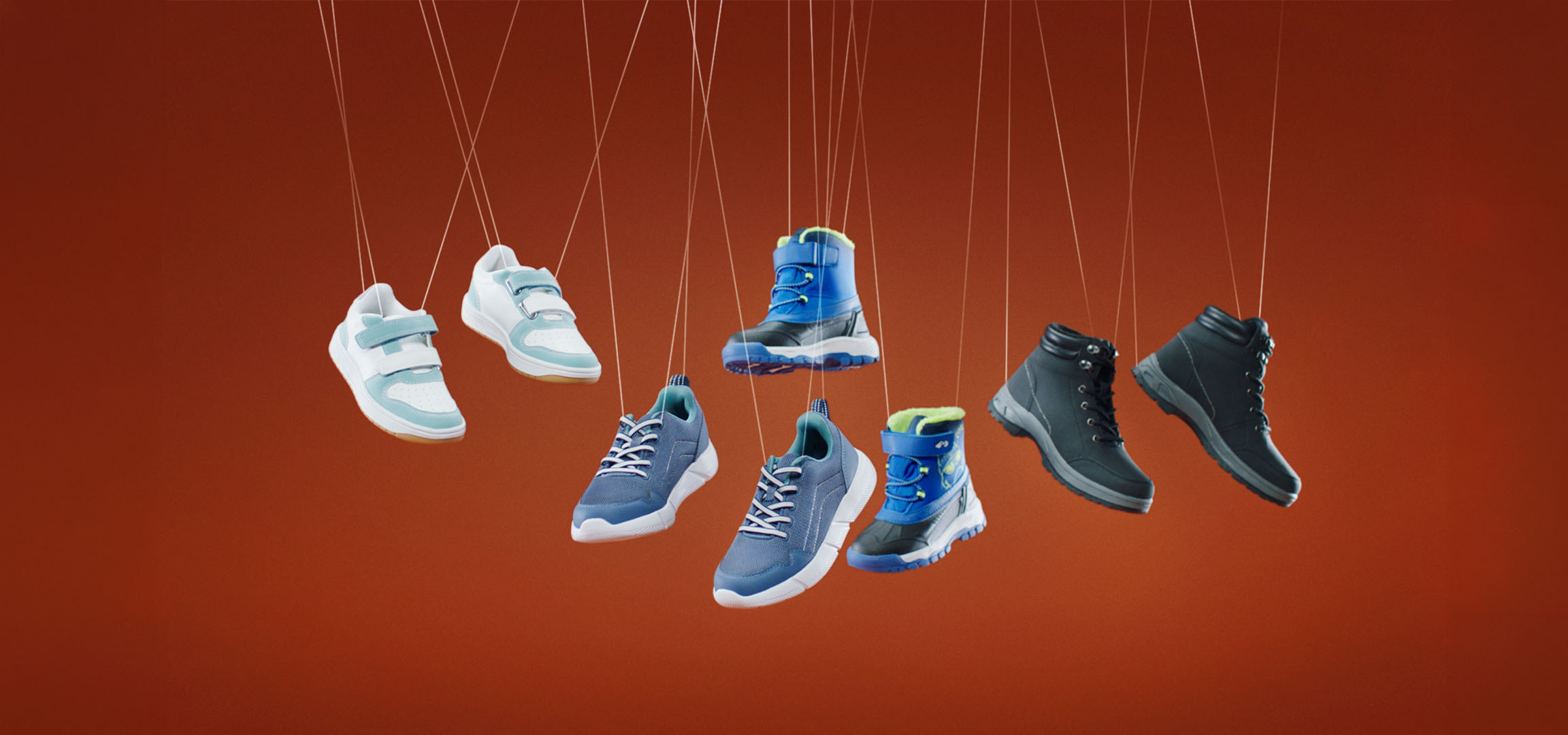 Diverse scarpe per bambini, tra cui sneakers e stivali, appese a dei fili.