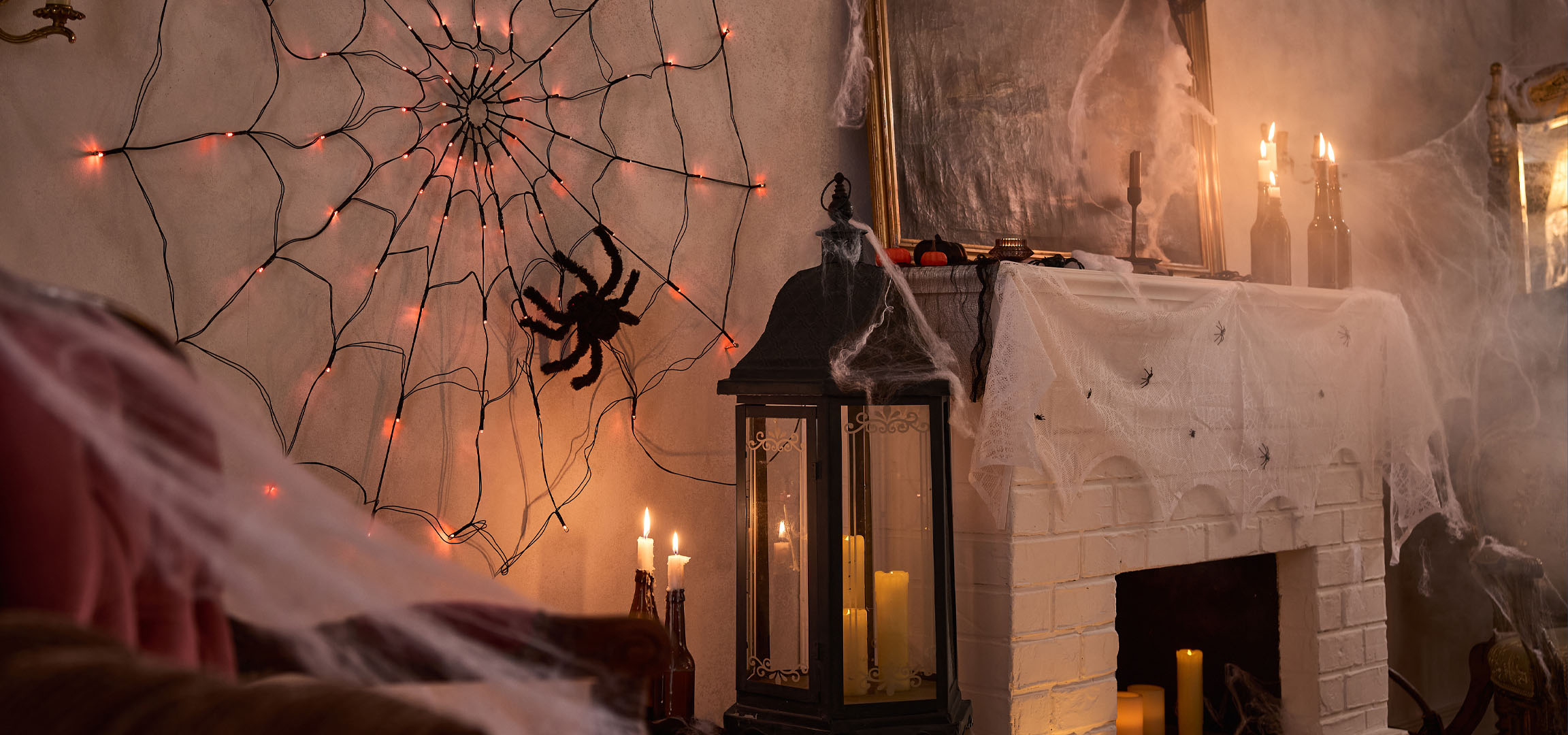 Decorazioni di Halloween con luci a ragnatela, un grande ragno e candele.