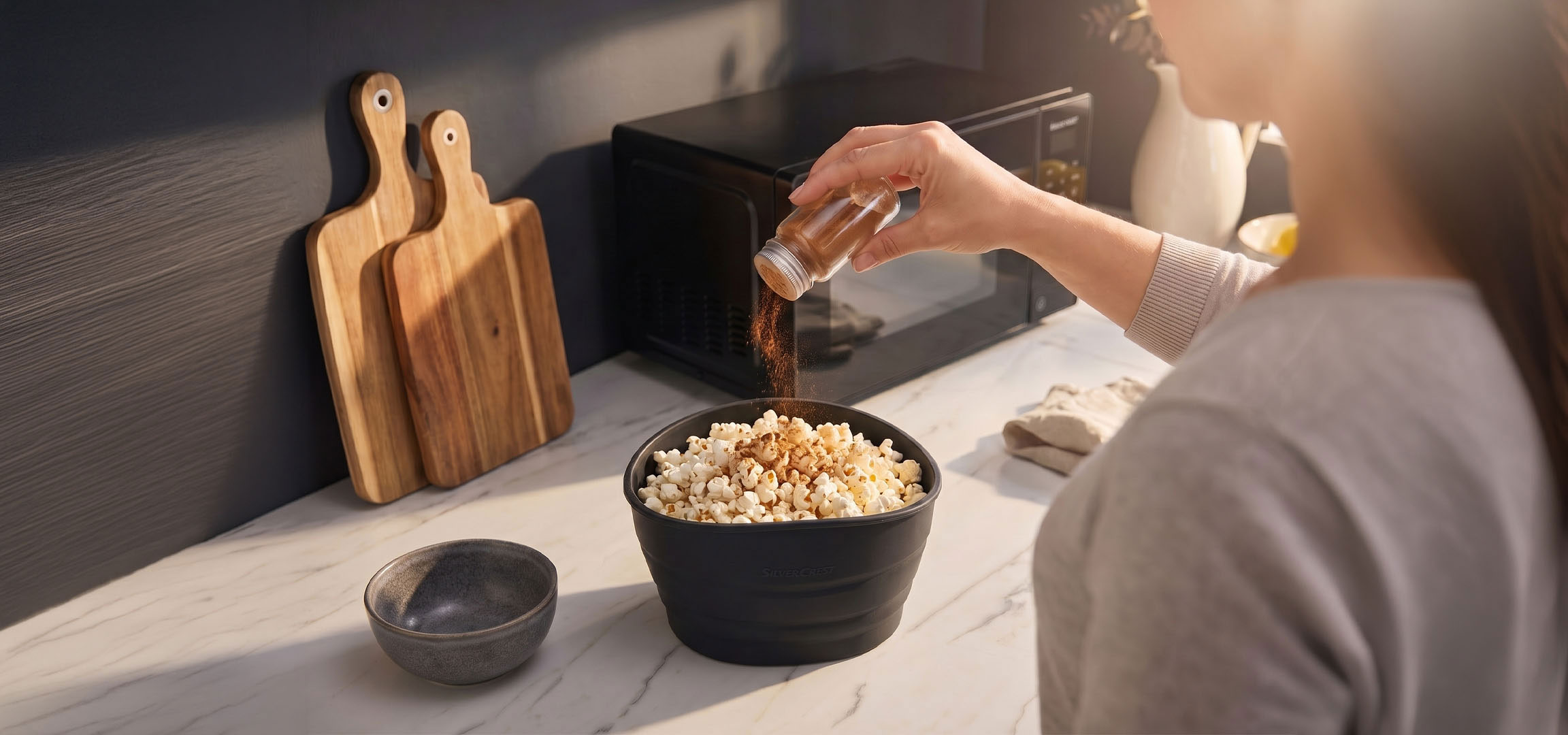 aiLabeling.aiLabelForImageAltText: Popcorn in una ciotola nera conditi con spezie, accanto a taglieri di legno.
