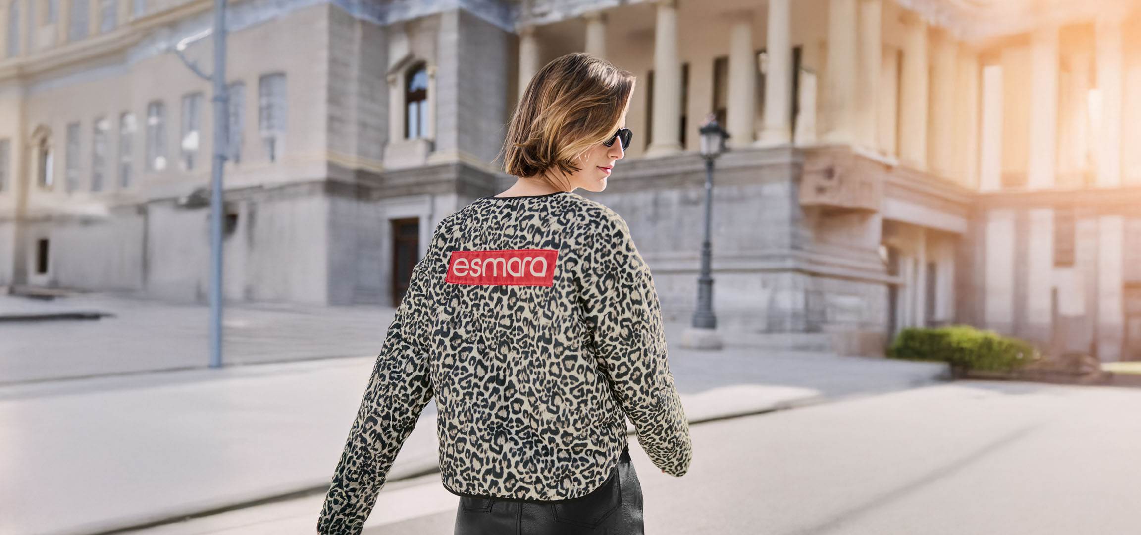 Donna con giacca leopardata Esmara, occhiali da sole, in una strada urbana.