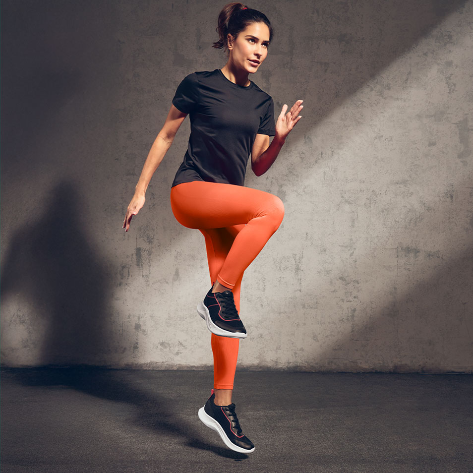 Donna in t-shirt sportiva nera e leggings arancioni che si allena