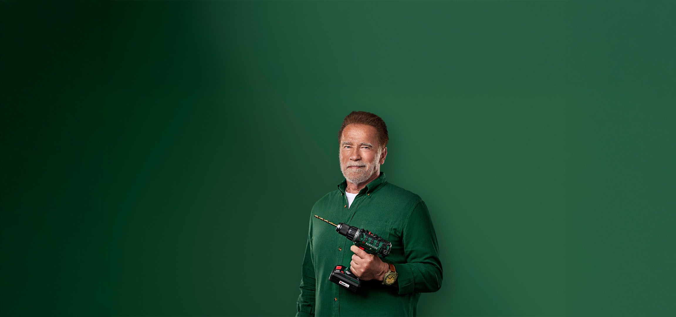 Arnold Schwarzenegger tiene un trapano Parkside su sfondo verde.