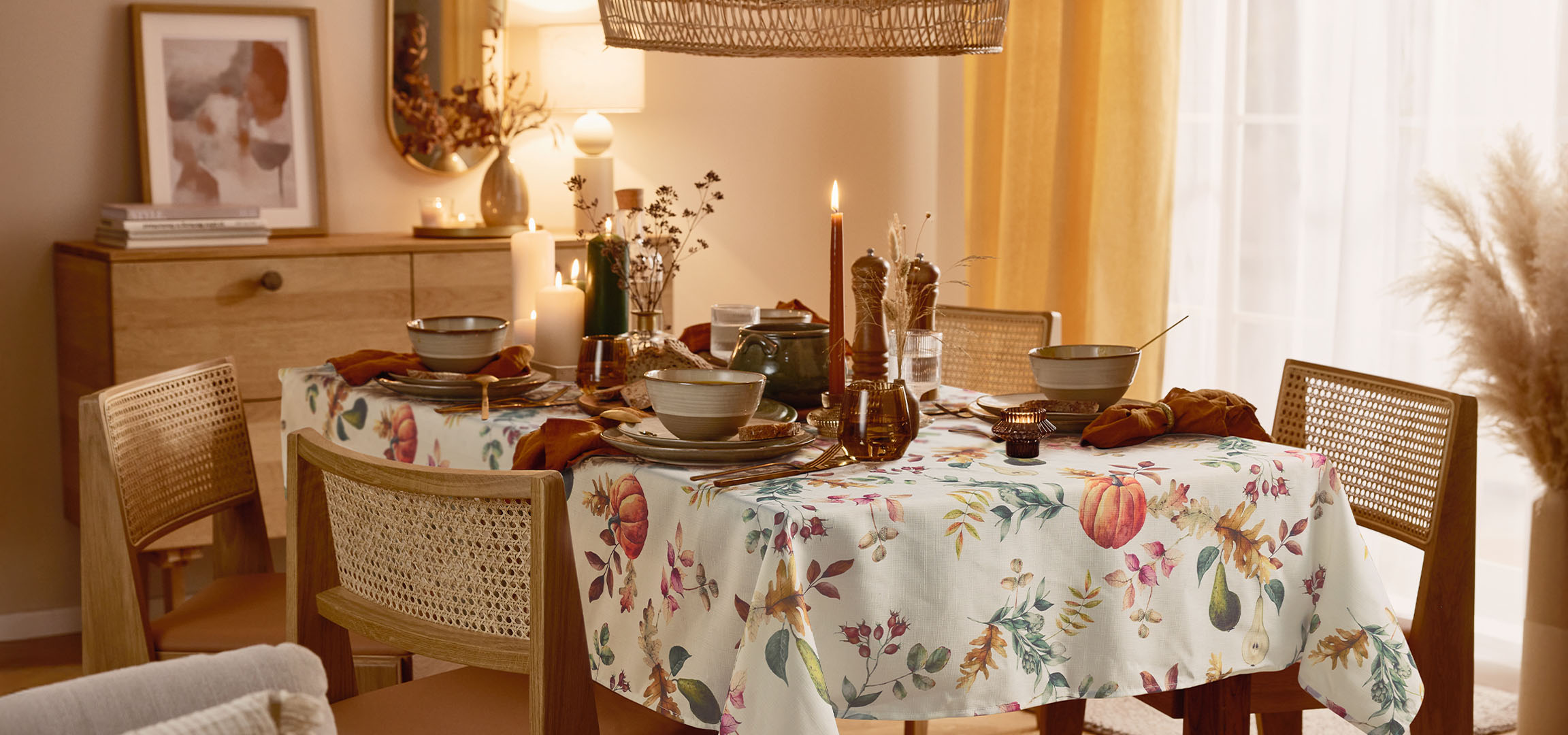 Sala da pranzo con tavolo apparecchiato, tovaglia floreale e illuminazione calda.