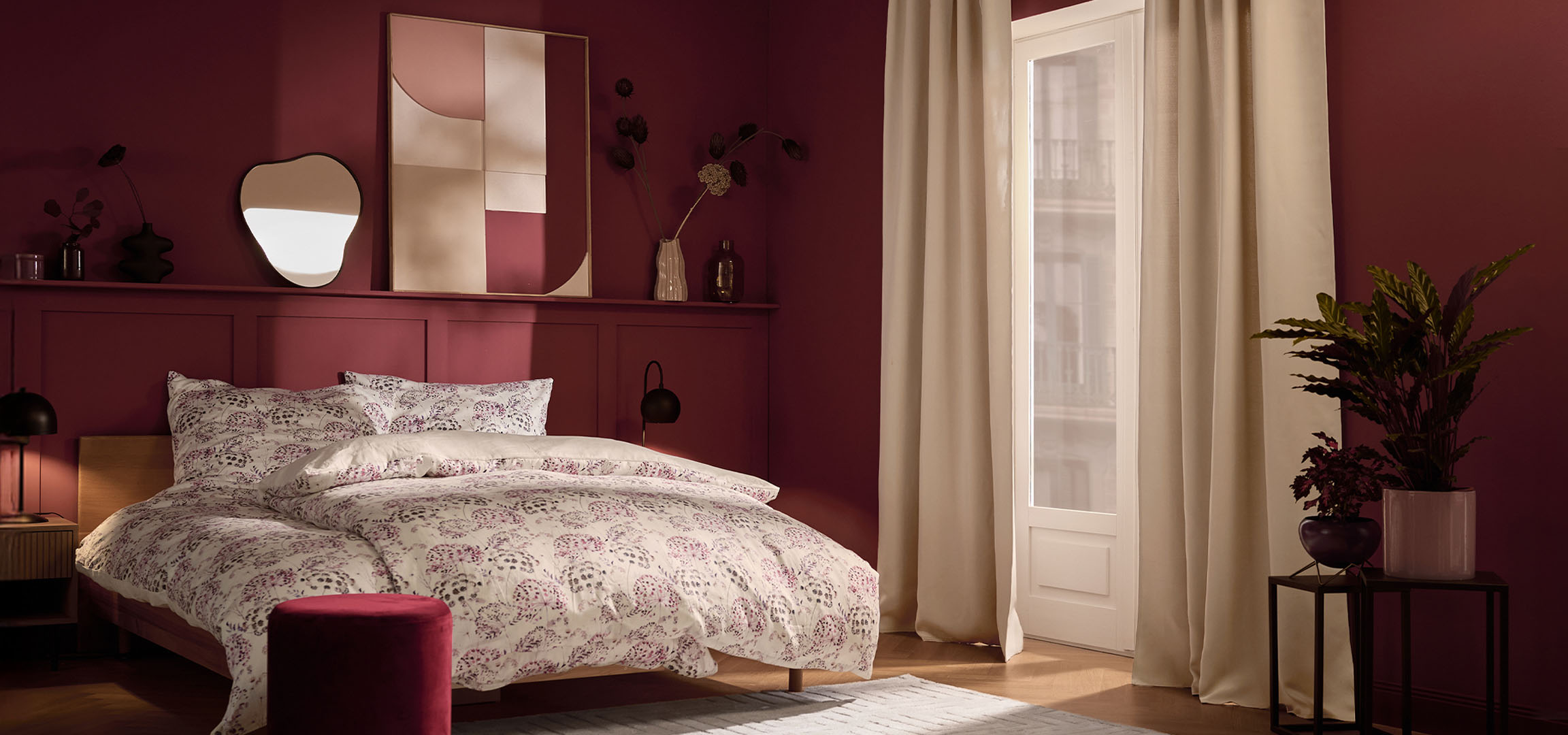 Camera da letto con pareti bordeaux, letto con biancheria da letto bianca a fantasia floreale e piante.