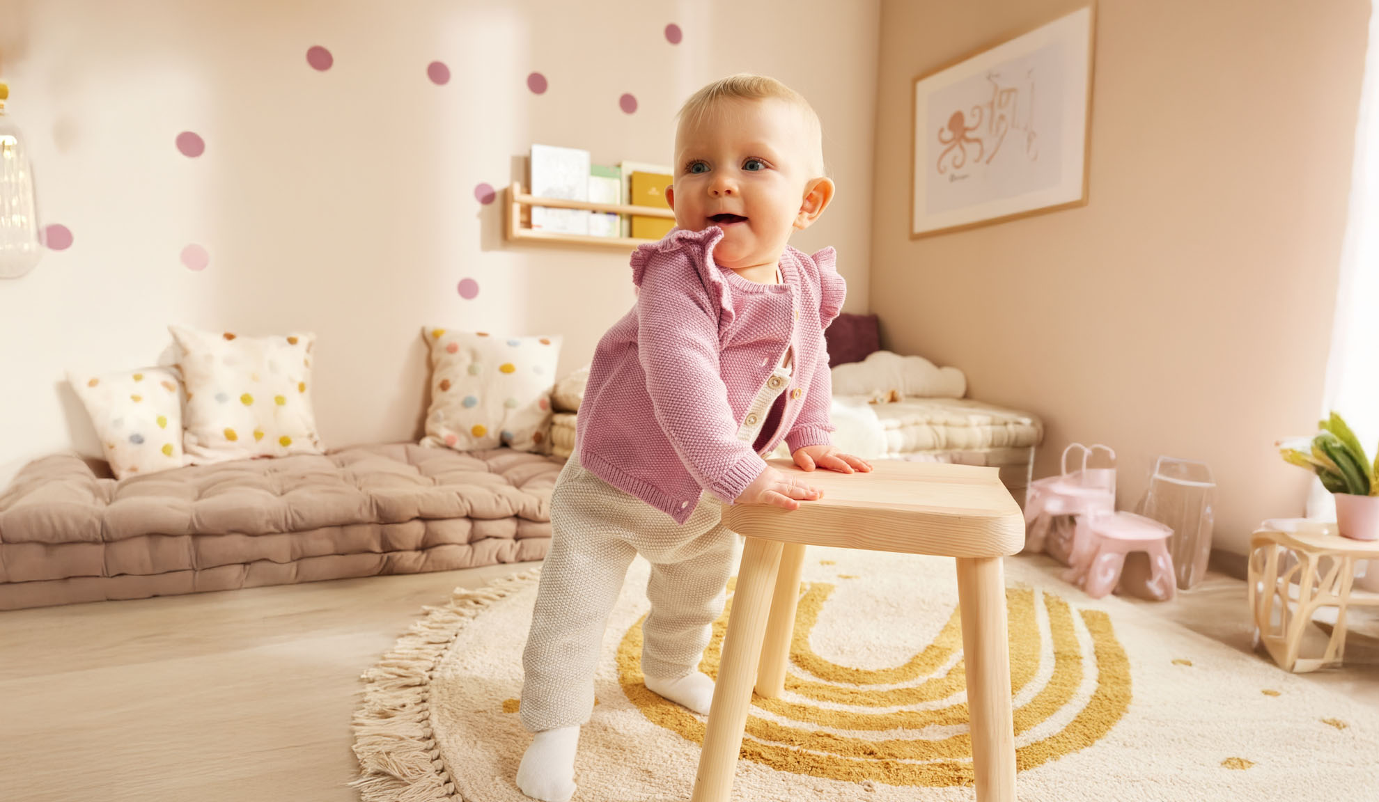 Un bambino piccolo in piedi vicino a un tavolino di legno in una stanza per bambini arredata in stile minimalista.