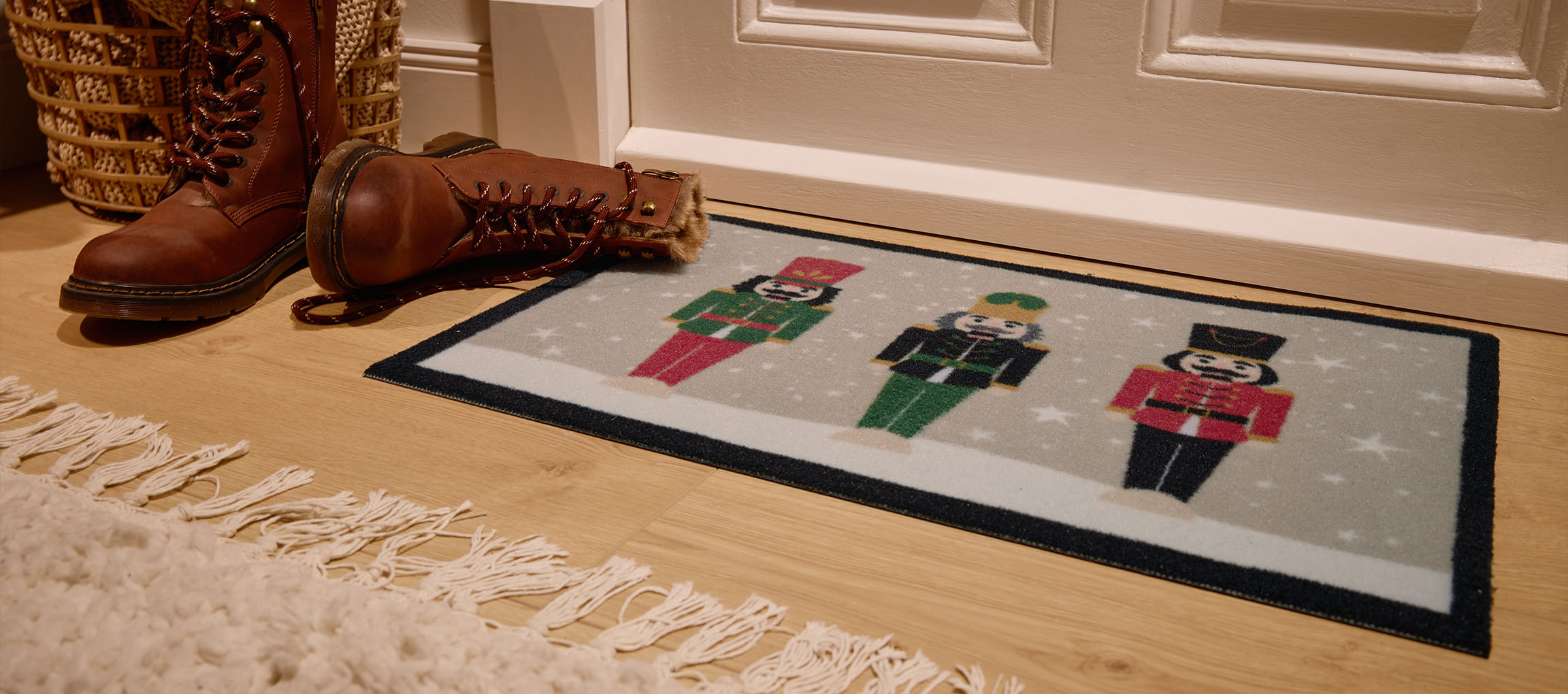 Zerbino natalizio con schiaccianoci, stivali marroni e cesto di vimini all'ingresso.