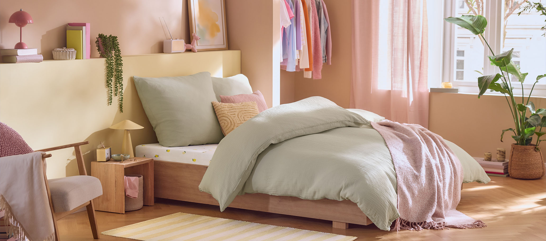 Camera da letto con letto in legno, biancheria da letto verde menta, cuscini e coperta rosa.