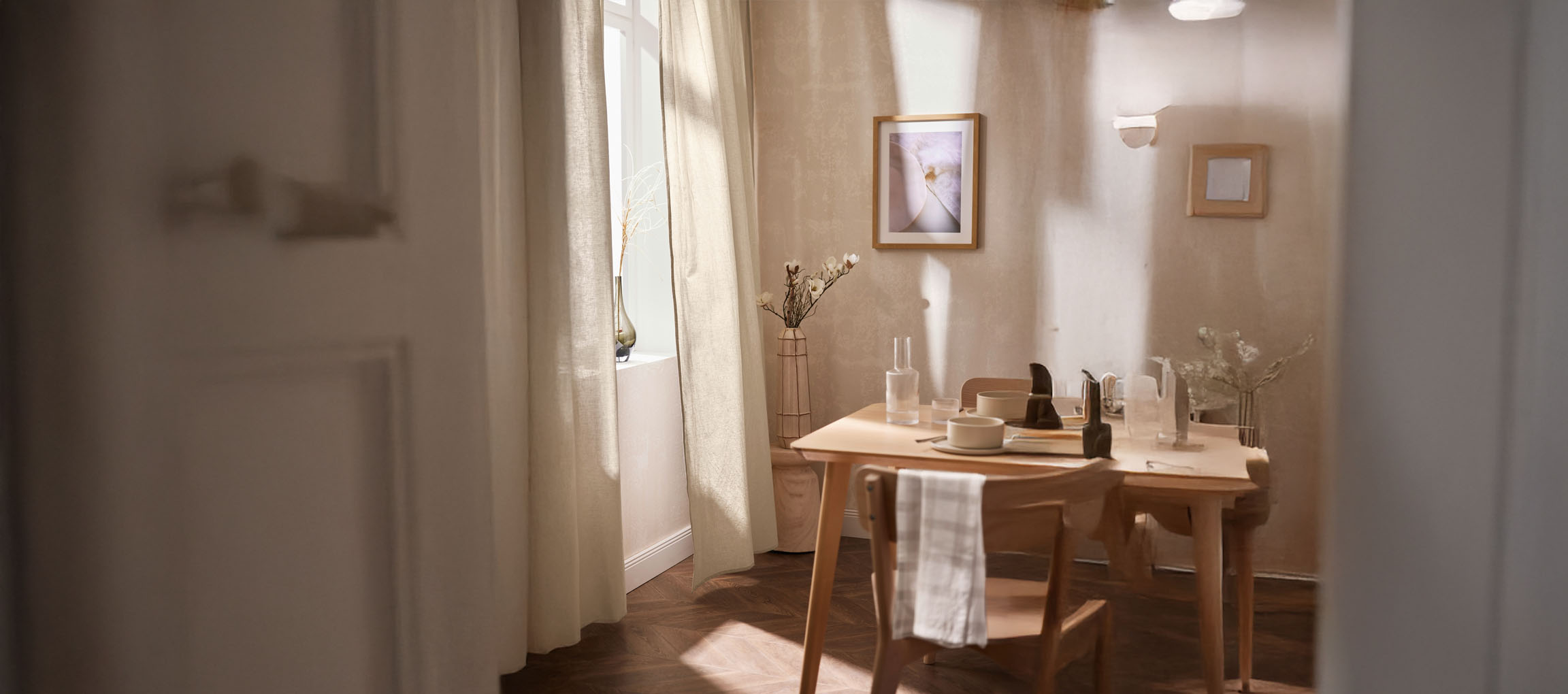 Sala da pranzo luminosa con tavolo in legno, sedie e decorazioni minimaliste.