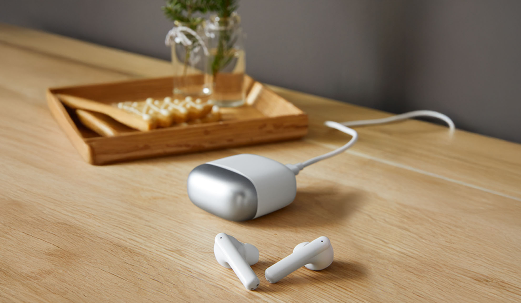 Auricolari bianchi e un dispositivo di ricarica su un tavolo di legno.