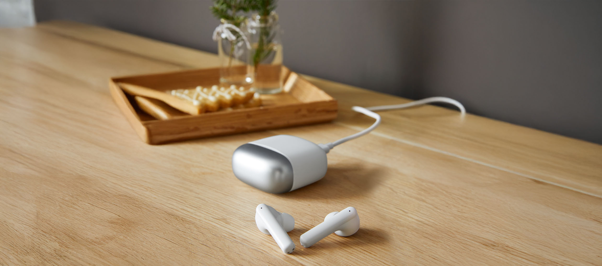Auricolari bianchi e un caricabatterie portatile su un tavolo di legno.