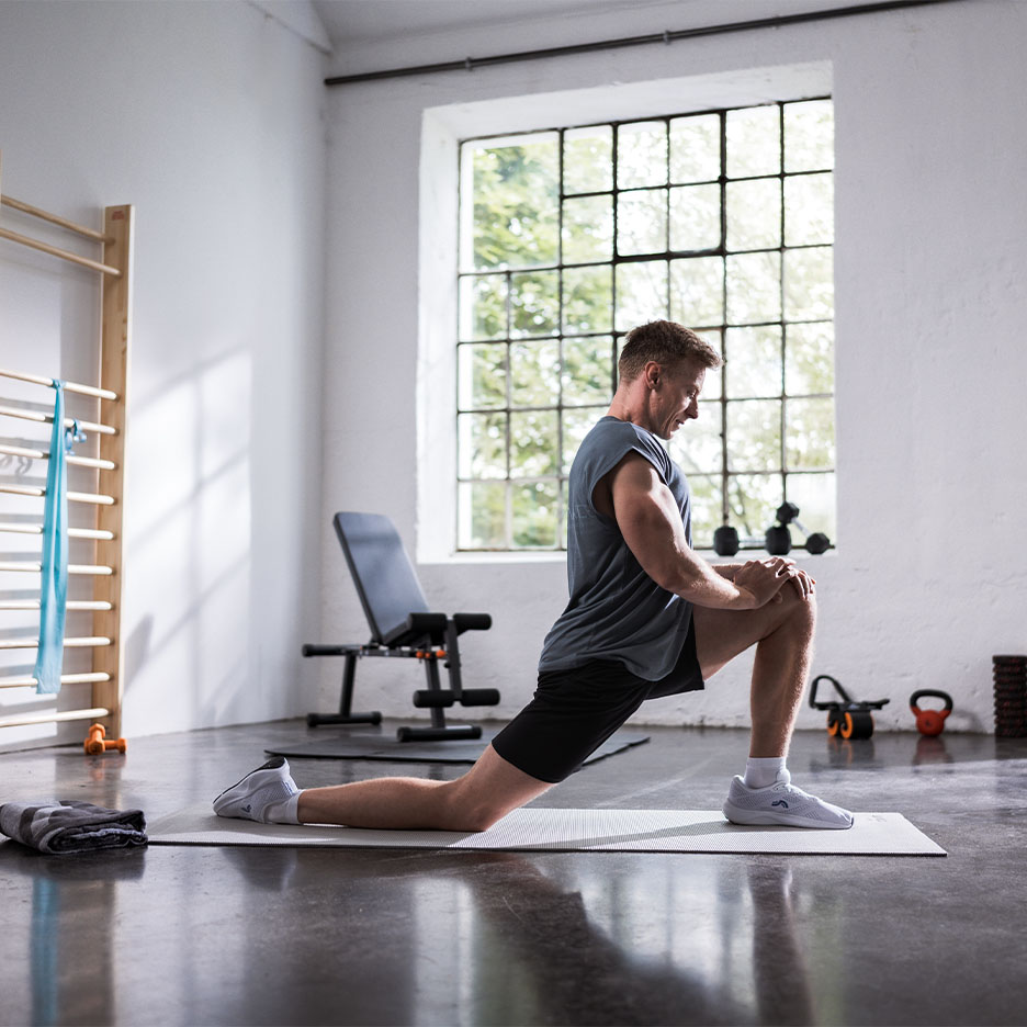 Uomo che si allunga su un tappetino da yoga in palestra.