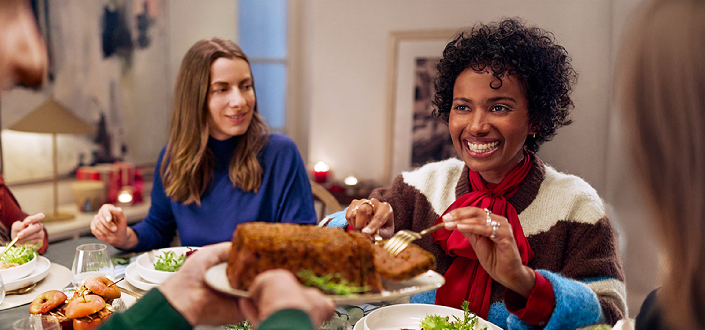 Tre donne sorridenti si godono una cena insieme in un ambiente accogliente.