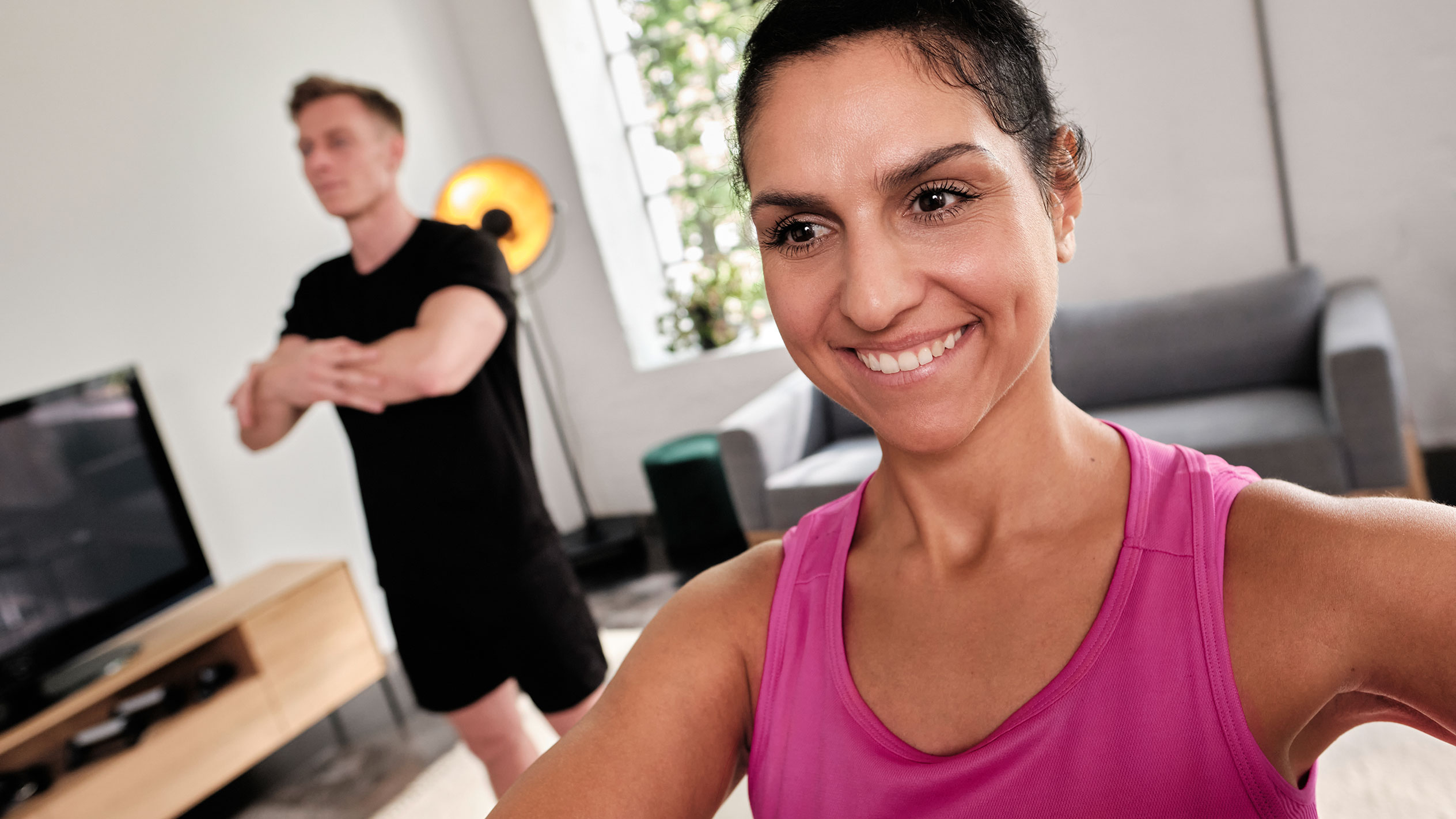 Donna sorridente che fa esercizio a casa con il suo partner.