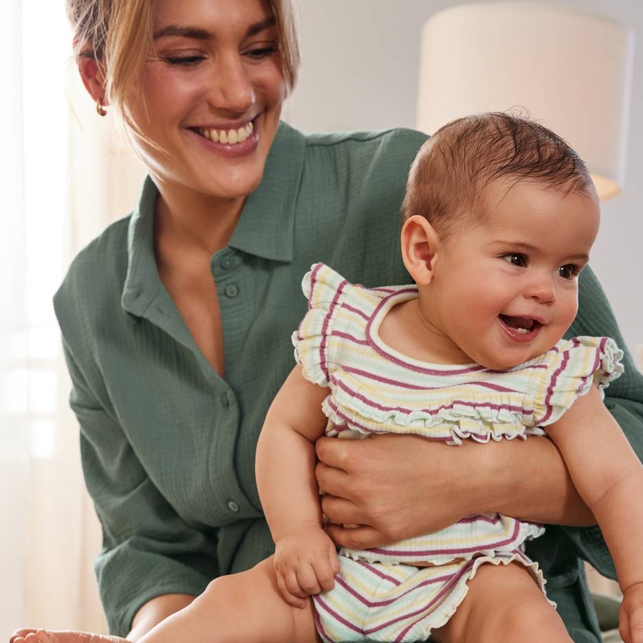 Mamma sorridente con un bambino felice che indossa un completo a righe colorate.