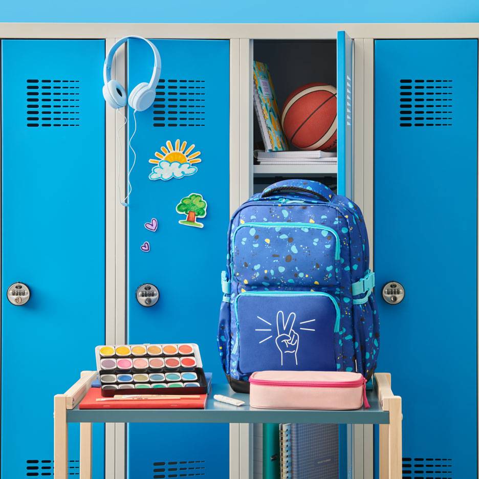 Zaino blu con segno di pace, acquerelli e cuffie davanti agli armadietti scolastici.