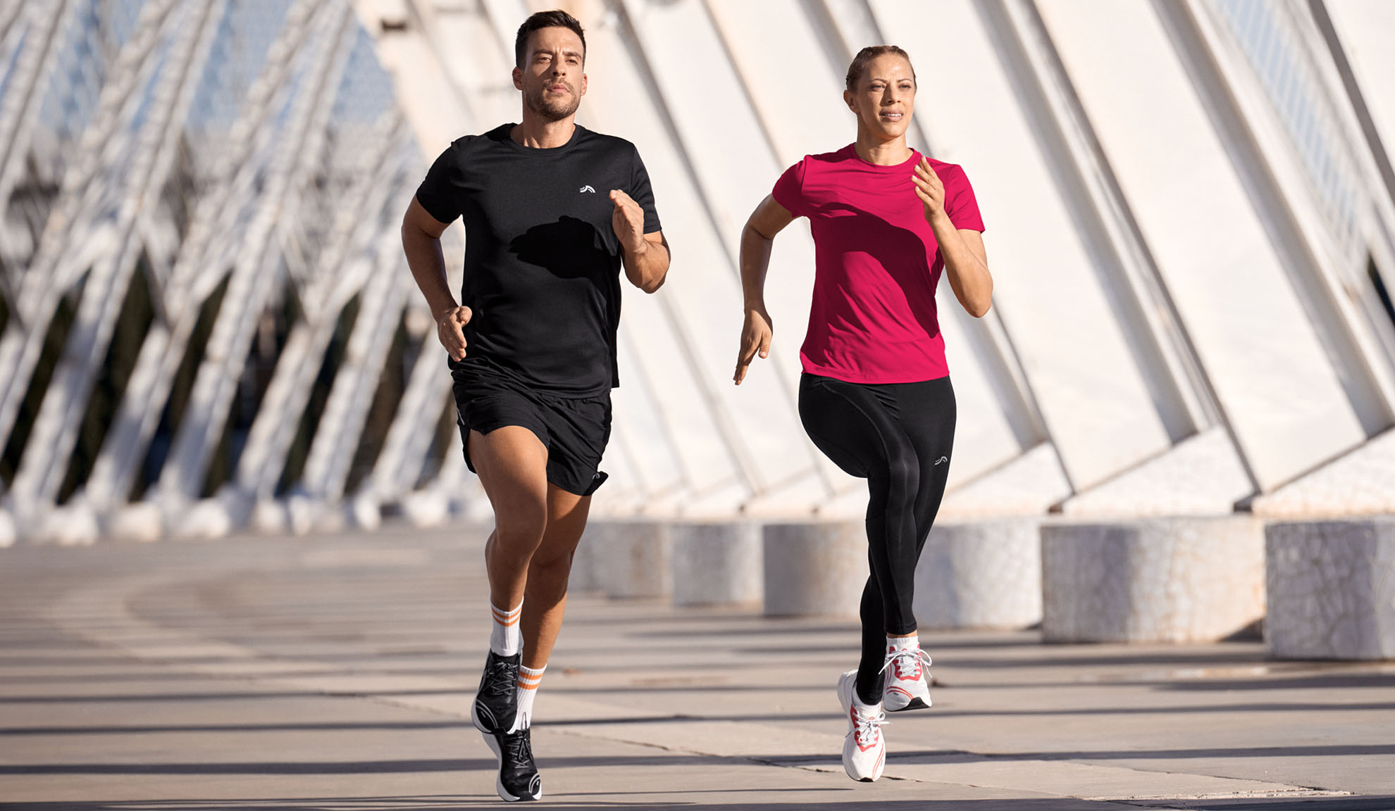 Uomo e donna corrono in abbigliamento sportivo, magliette e leggings.