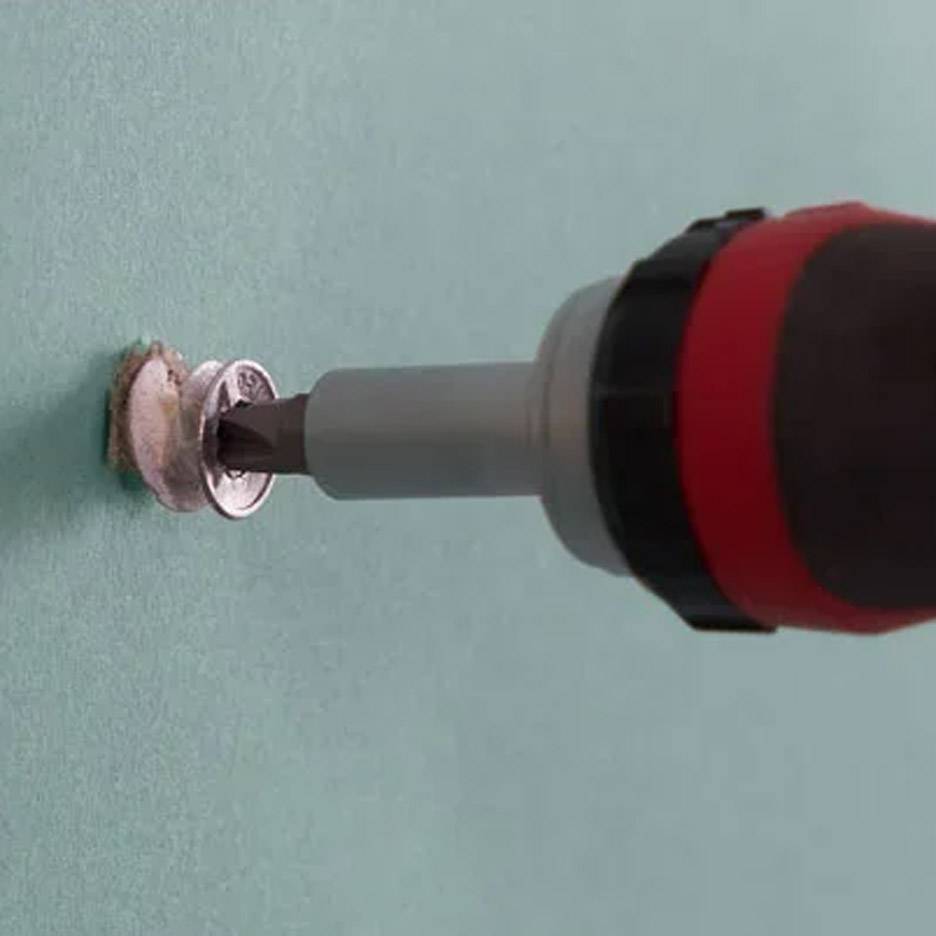 Cacciavite elettrico con punta da trapano che inserisce una vite nel muro.