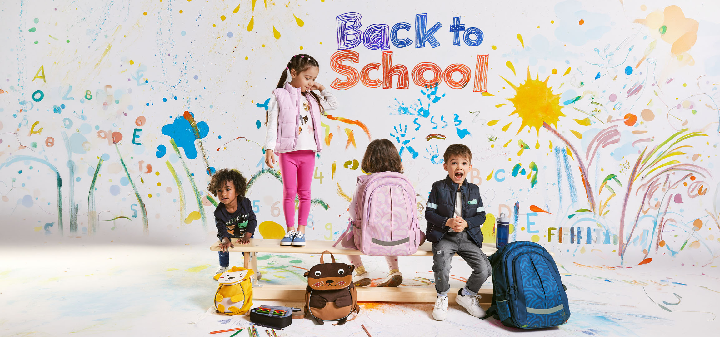 Bambini con zaini e materiale scolastico su uno sfondo di disegni colorati con la scritta