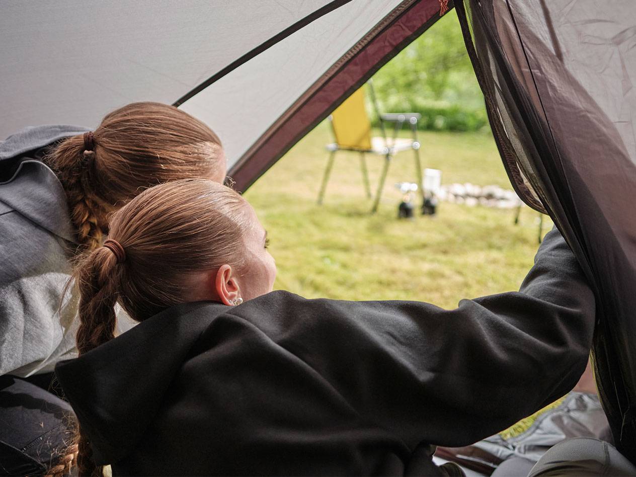 Due ragazze guardano dall'apertura di una tenda.