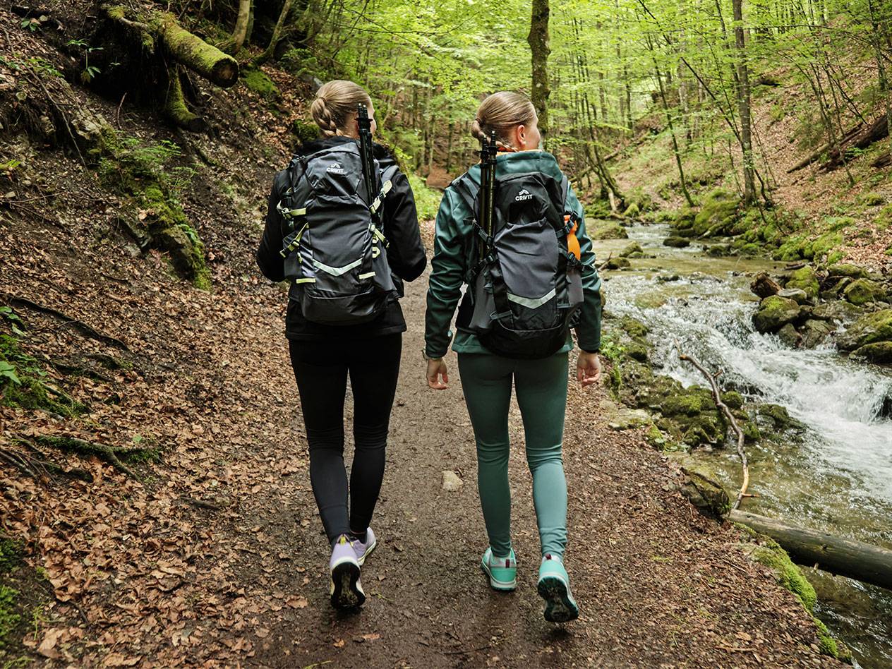 Due donne con zaini Crivit camminano su un sentiero nel bosco.